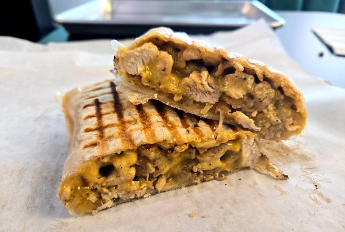 A French tacos, sliced in half, revealing chicken, cheese, and French fries