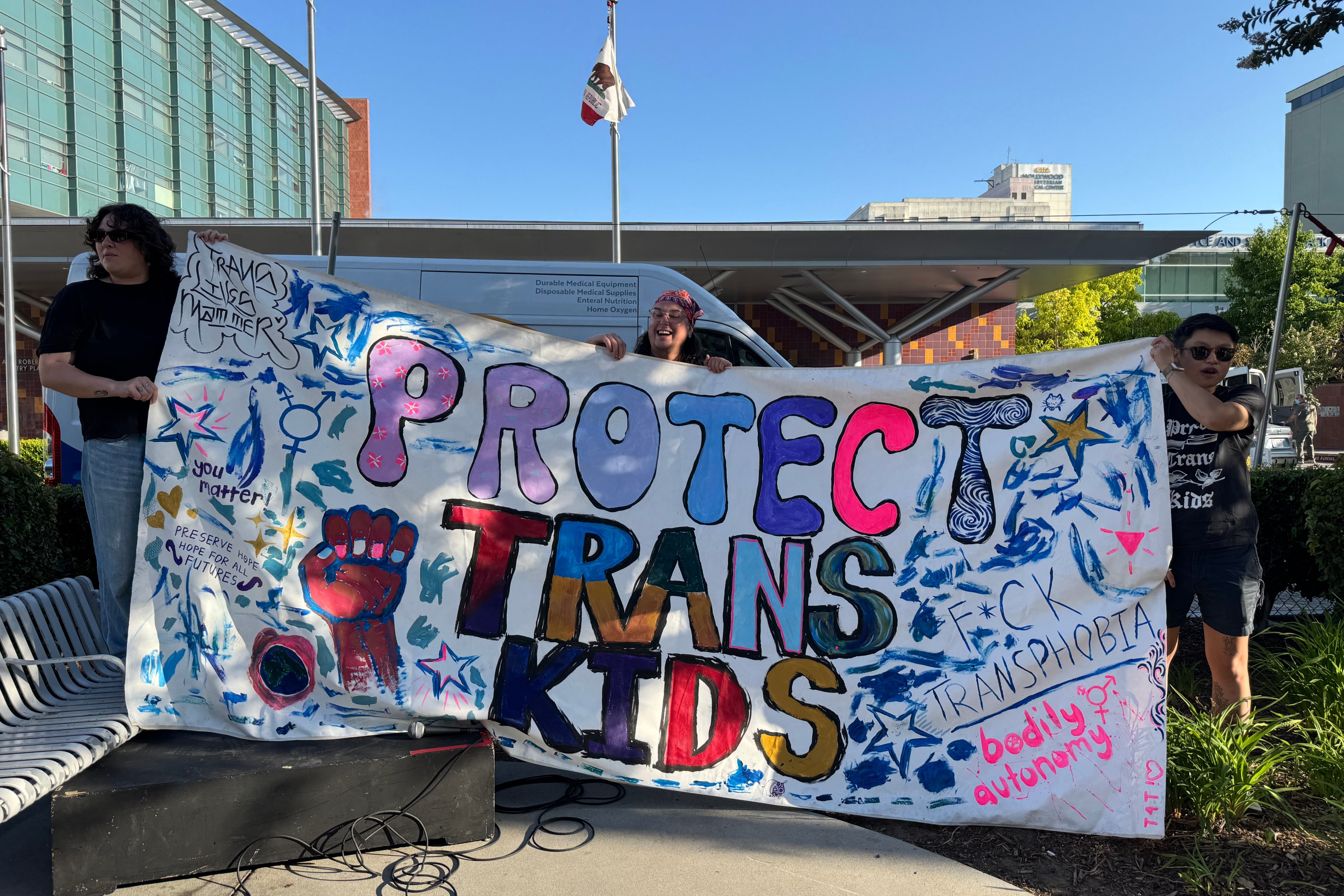 Protestors outside of Childrens Hospital LA holding a sign that says "Protect Trans Kids"