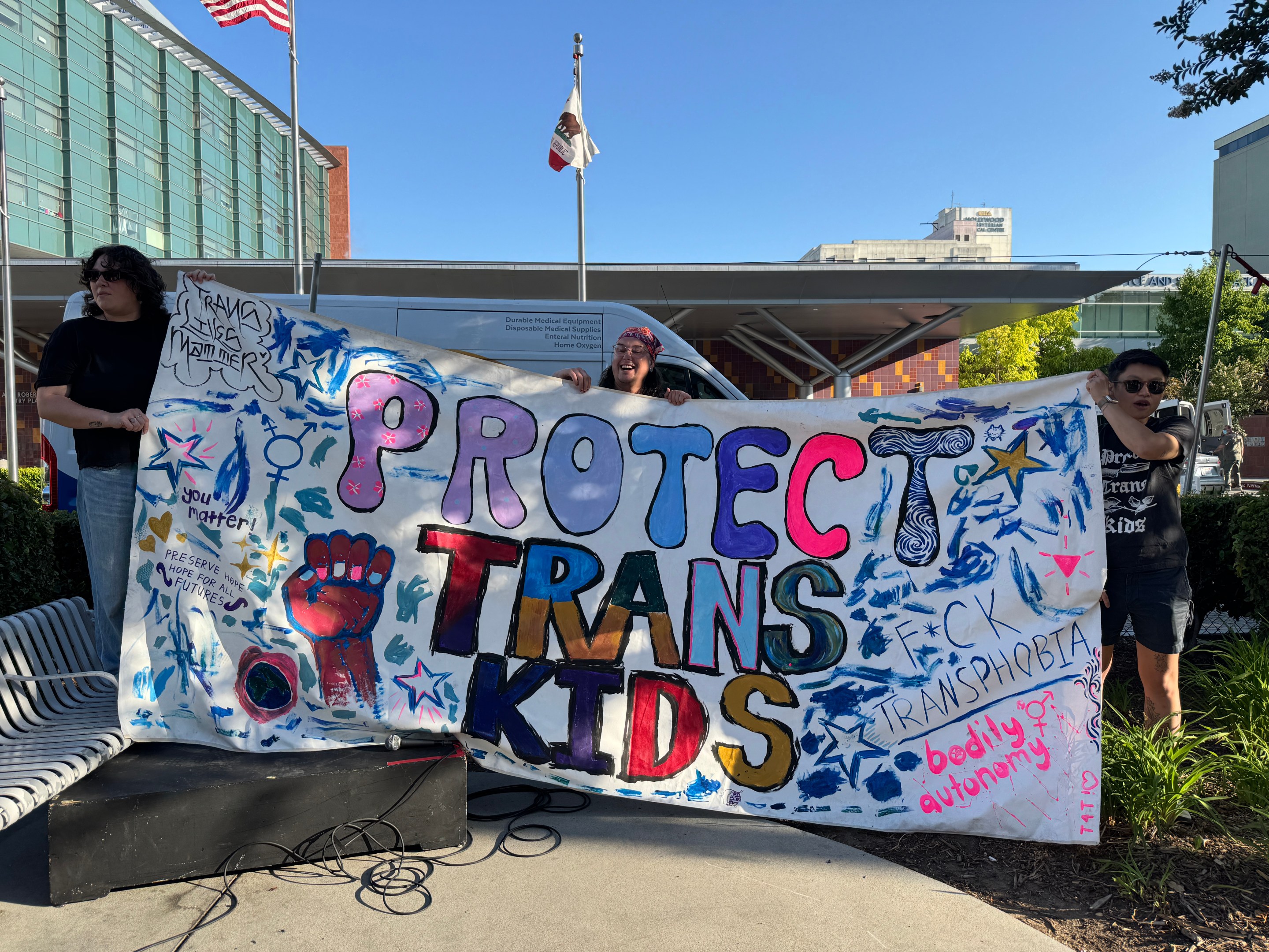 Protestors outside of Childrens Hospital LA holding a sign that says "Protect Trans Kids"