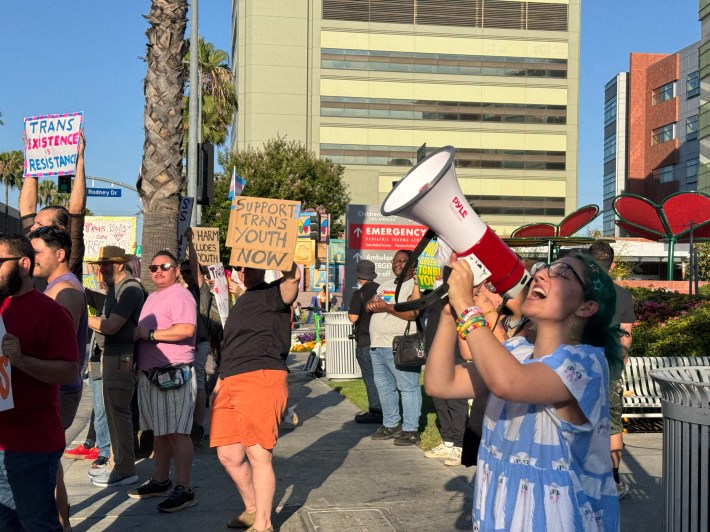 A woman yells into a bullhorn in front of other protesters