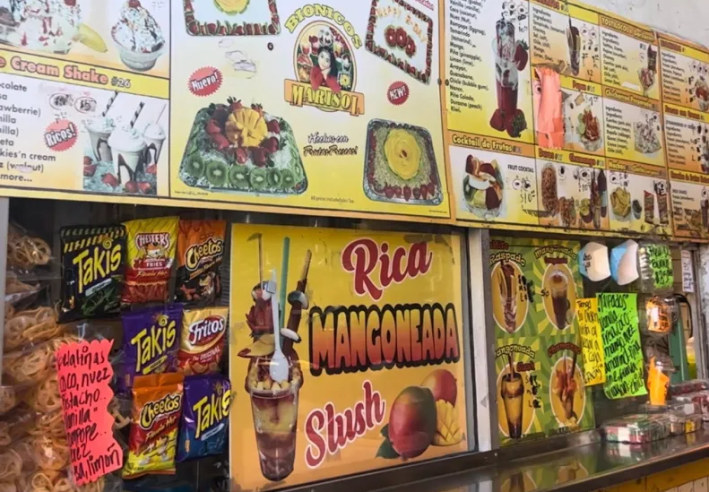 A partial look at the yellow menu posted at Bionicos Marisol, which shows chips, bionicos, and mangoneadas ricas.