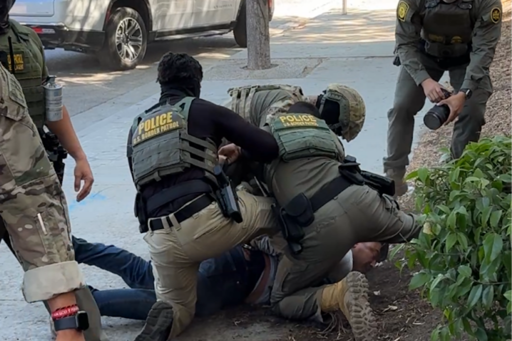 A man being wrestled to the ground by Border Patrol agents.