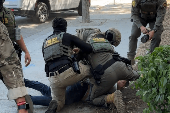 A man being wrestled to the ground by Border Patrol agents.