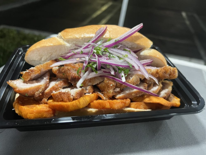 A Chicharron sandwich at Sazon Con Corazon fille with fried pork belly and red onions.