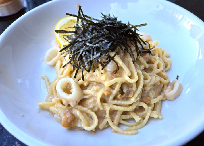 Spaghetti with cod roe, squid, and sea urchin at Unetto, topped with seafood flakes and with a lemon behind it all