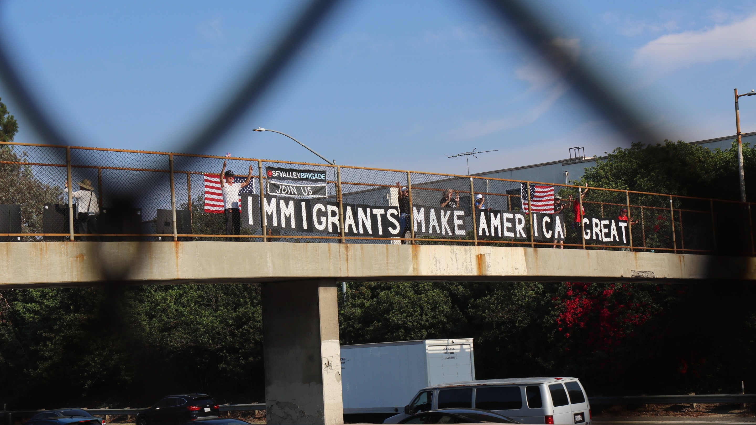The San Fernando Valley Brigade, stand on both sides of the overpass overlooking the 101 freeway waving at L.A.'s morning commuters after placing their "Immigrants Make America Great Sign." Photo by Janette Villafana for L.A. TACO.