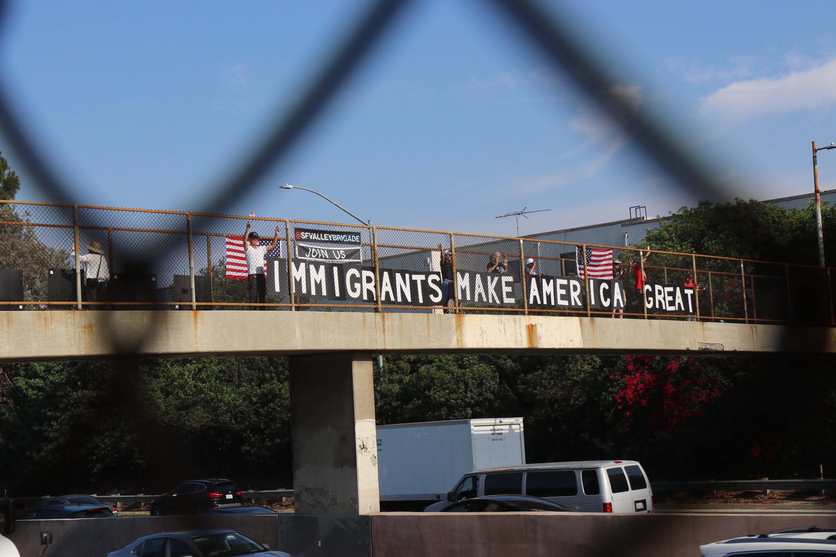 The San Fernando Valley Brigade, stand on both sides of the overpass overlooking the 101 freeway waving at L.A.'s morning commuters after placing their "Immigrants Make America Great Sign." Photo by Janette Villafana for L.A. TACO.