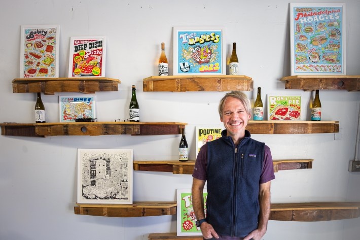 Kings Carey winemaker James Sparks, in front of colorful framed prints by artist Hawk Krall gallery at his Solvang tasting room. Photo by Janelle Koch.