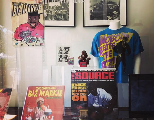 A collection of Biz Markie-related gear at an LA ice cream shop, including a Source magazine cover, Biz Markie cereal, and a t0shirt with Biz Markie on it.