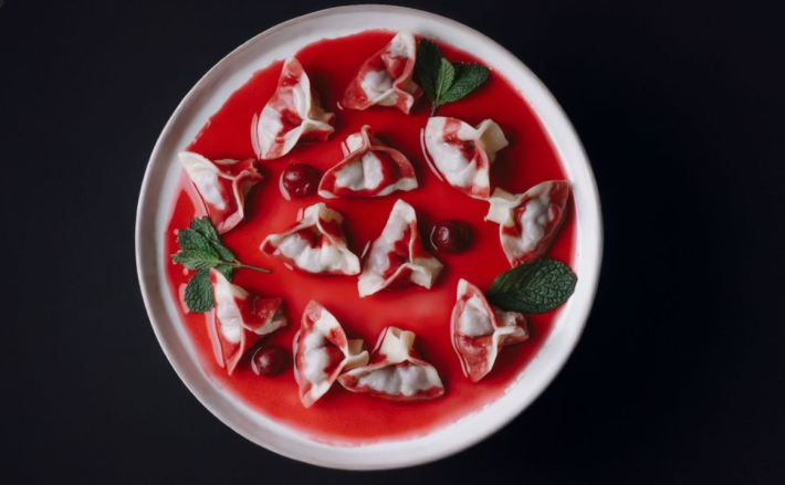 A white plate with sour cherry vareniki and mint leaves