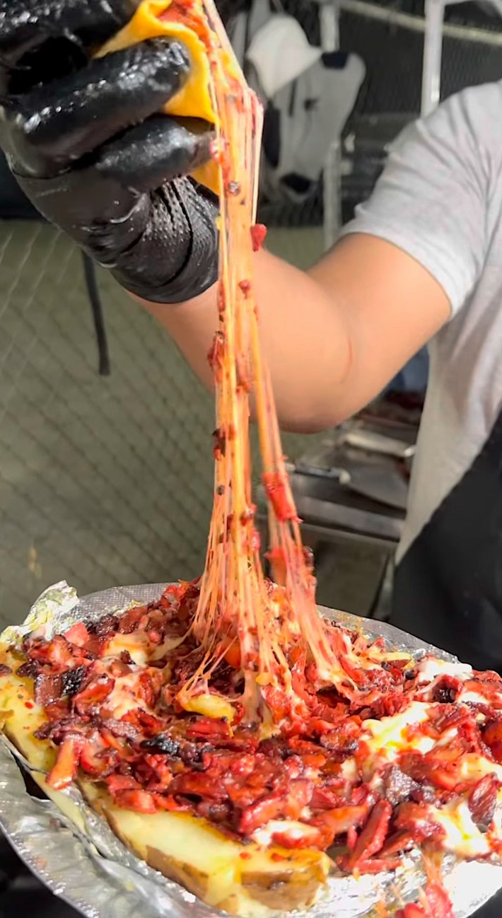 a huge cheese pull from a plate of papas locas in Altadena