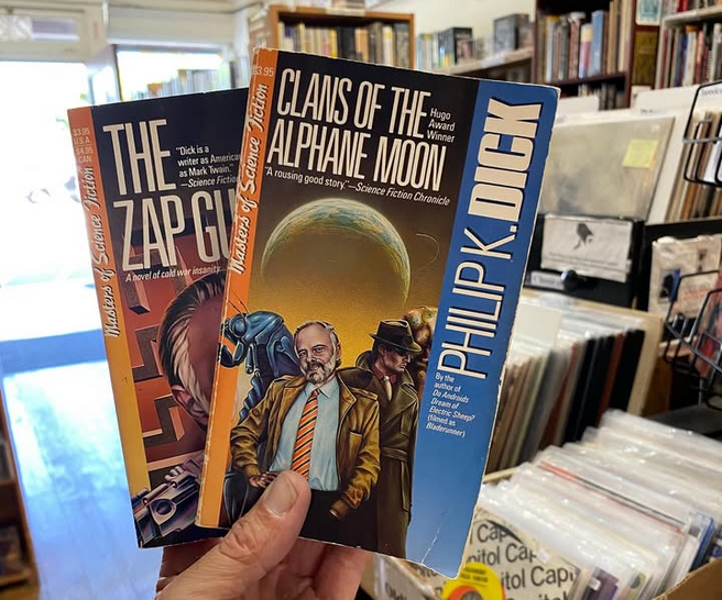 2 Philip K. Dick paperback books in the hands of a person
