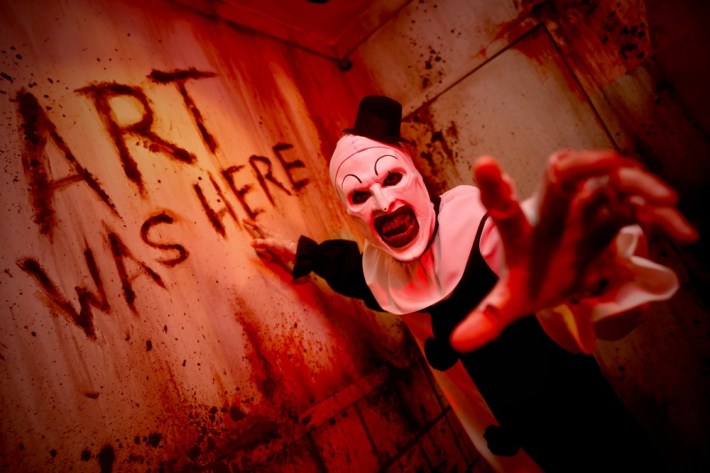 Art the Clown from Terrifier pointing to blood on the wall spelling out Art Was Here