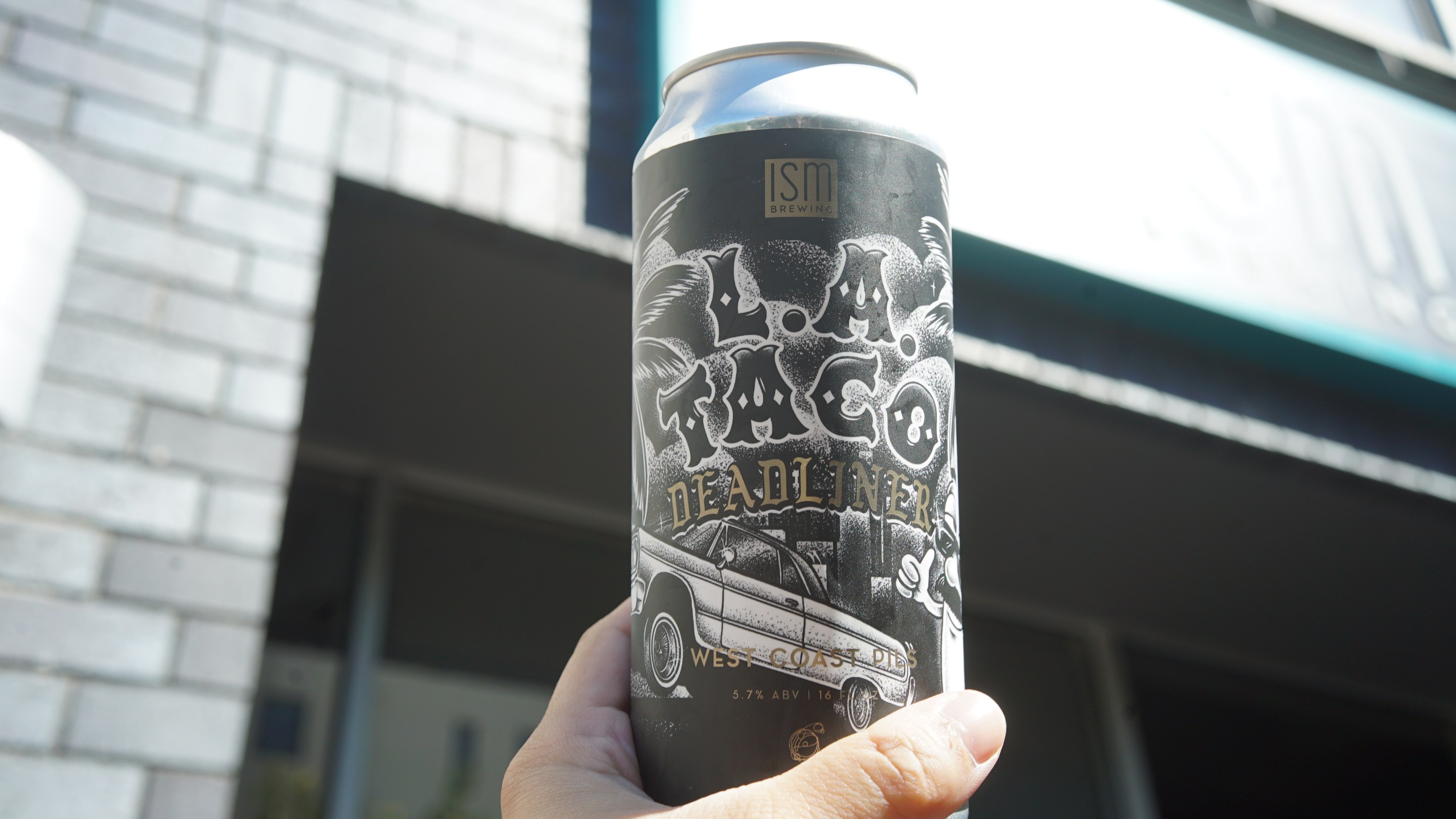 A can of beer with black and white label being held by hand.
