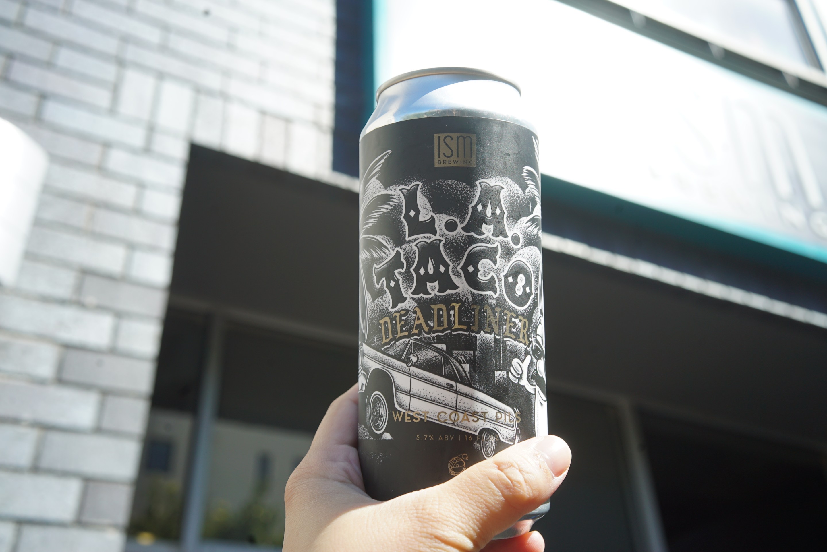A can of beer with black and white label being held by hand.