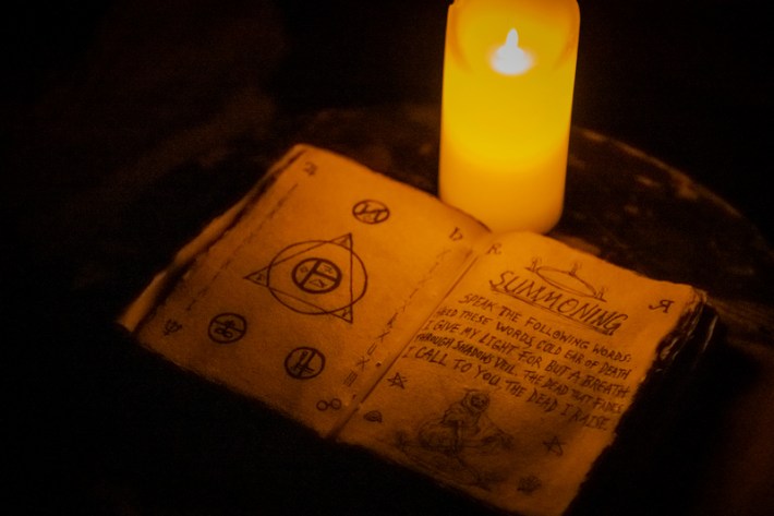 An open spellbook filled with runes and symbols beside a candle