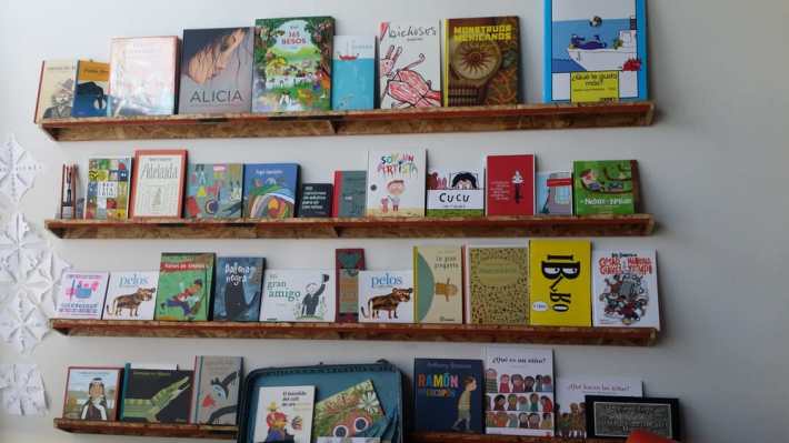 shelves full of children's books in Spanish.