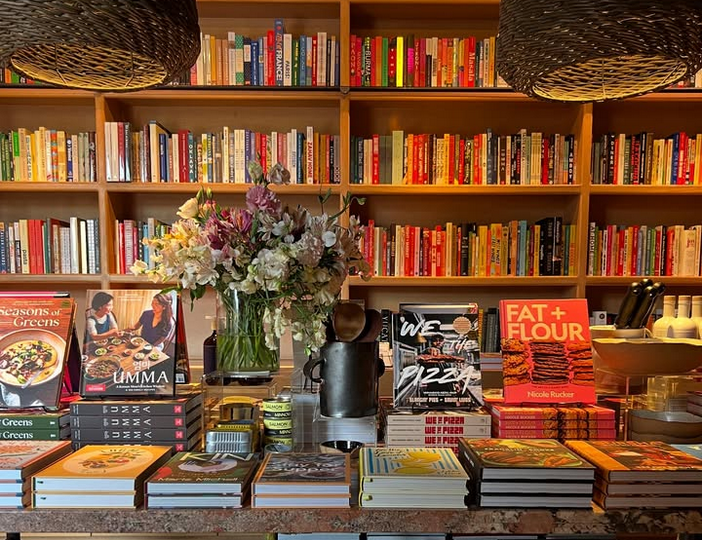 Books and flowers on a table with shelves of books in the background