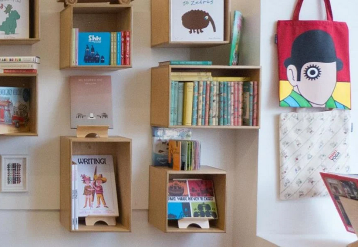 Books and art displayed at a bookstore, including a stylized depiction of the protagonist of Clockwork Orange on a tote bag