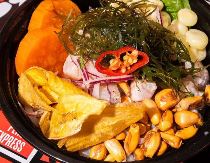 Ceviche with fish, dried and fresh corn, seaweed, yam, and plantain chips in a black plastic bowl