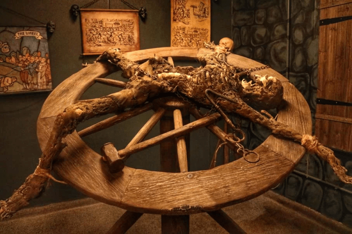 A medieval breaking wheel torture device with a skeleton on top