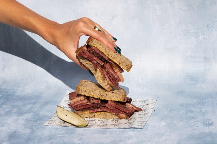 Red-oak smoked Wagyu pastrami on Bub & grandma's bread being held in a lady's hand