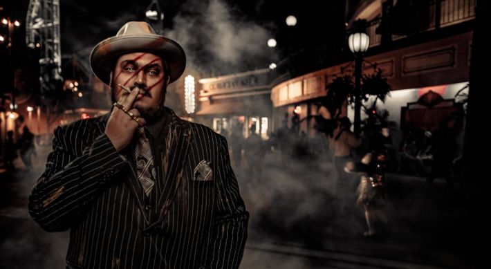 A 1920's style gangster who is also a zombie in a pinstriped suit, with big slashes on his face, smoking a cigarette