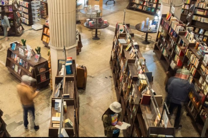 An overhead view of a bookstore with Corinthian columns, where people browse the aisles and look at books