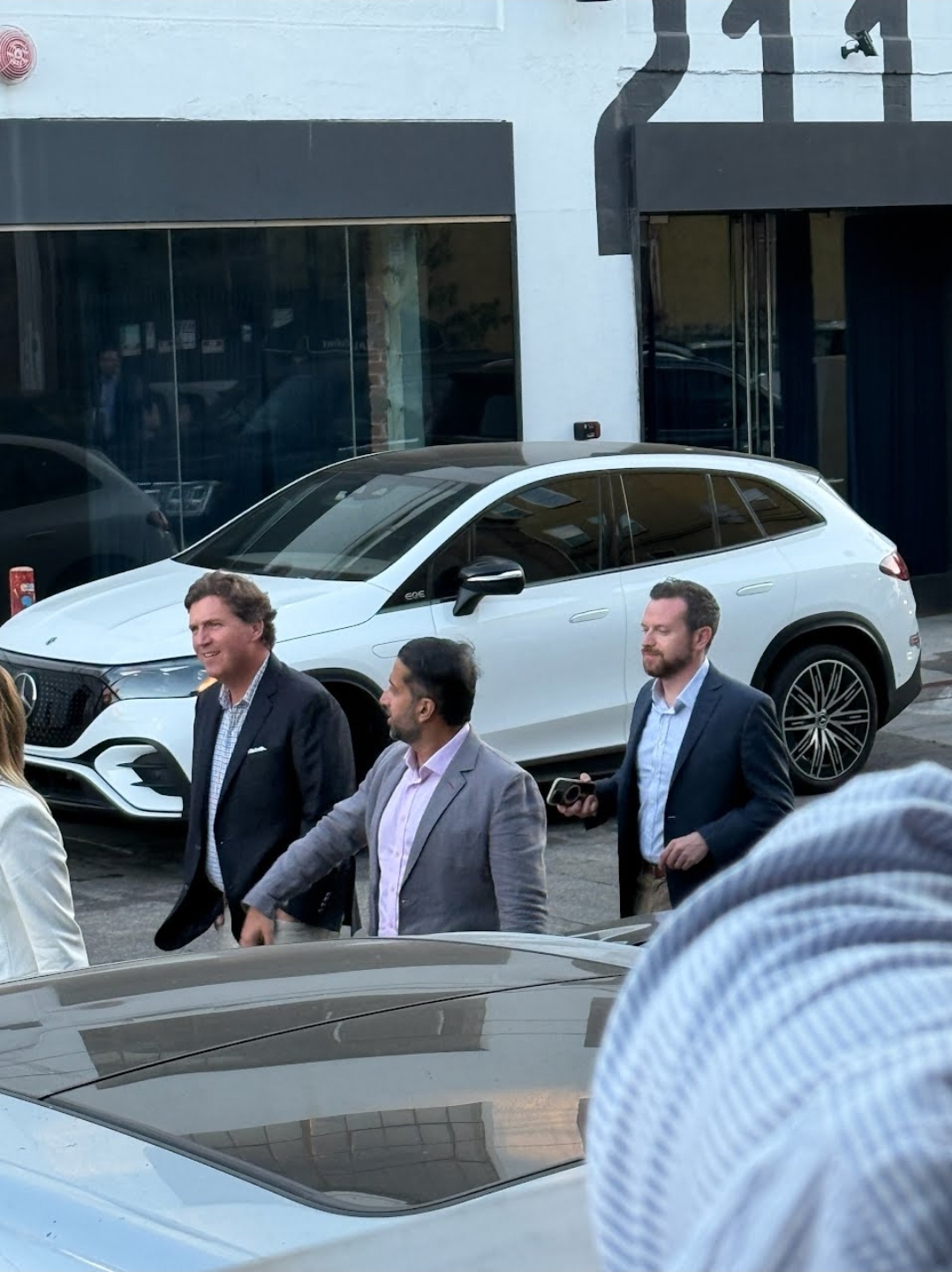 Tucker Carlson walks with two identified men outside of Damien.