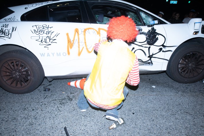 A man squats to vandalize a car