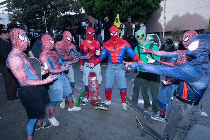 Several people dressed as Spiderman point at one another