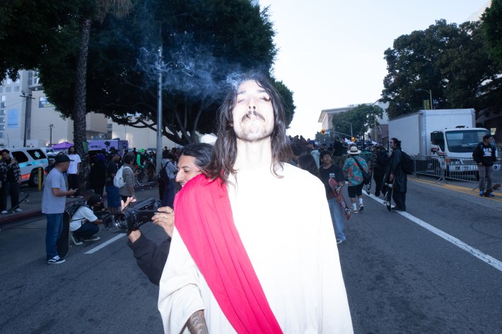 A man dressed as Jesus blows smoke from a joint