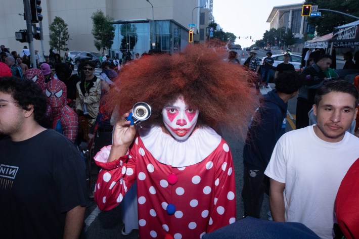 a girl in clown makeup looks into the camera spookily