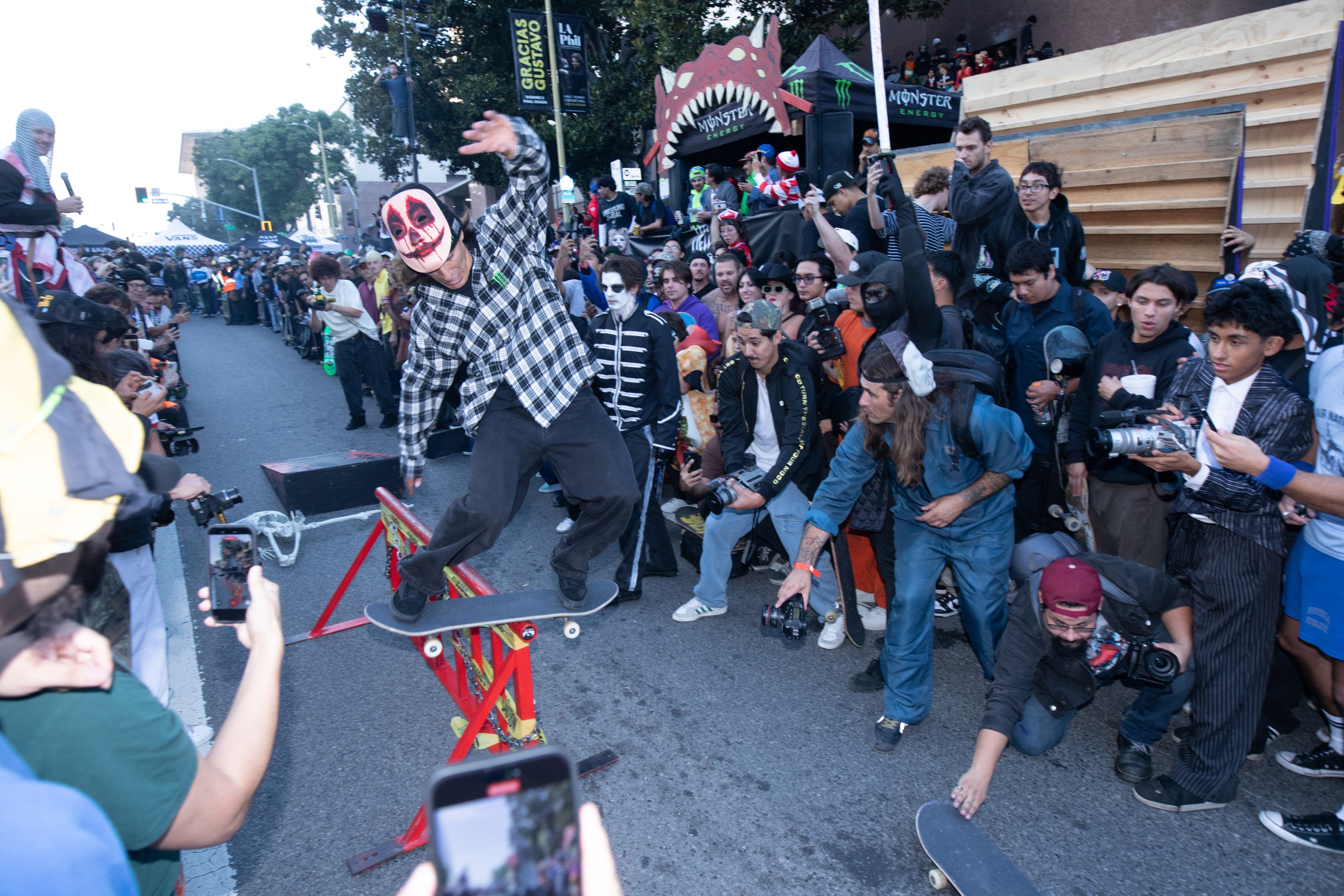 A skater in a clown mask does a trick in front of a crowd