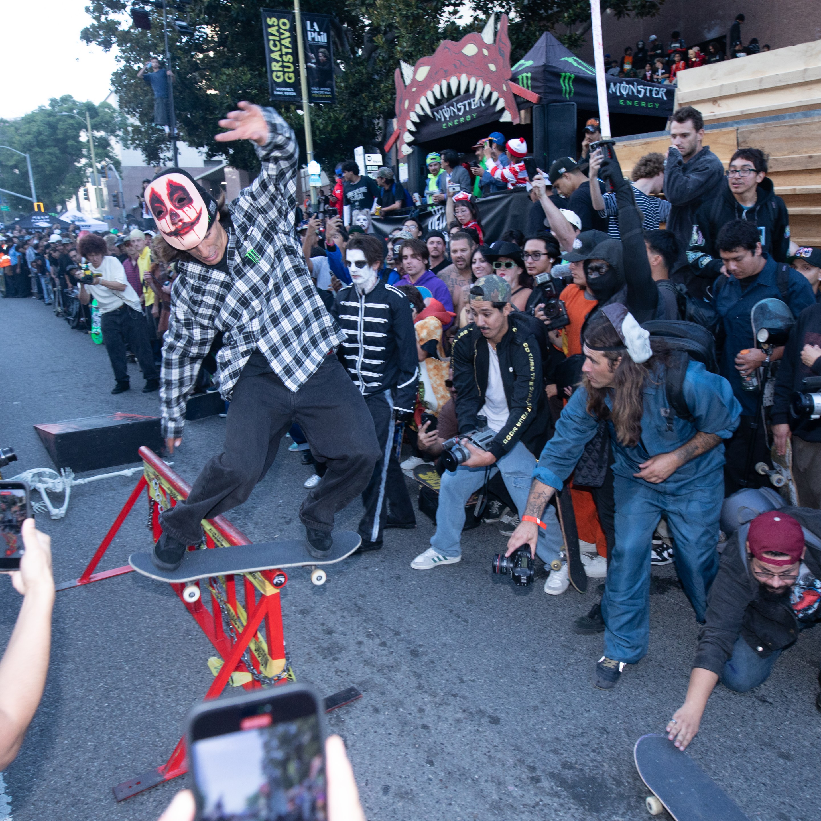 A skater in a clown mask does a trick in front of a crowd