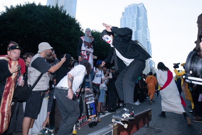A crowd of people watch a man do a skateboard trick