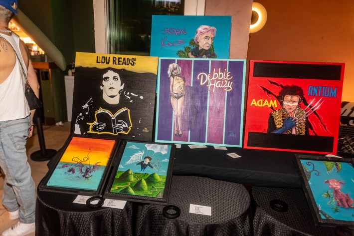 Various pieces of colorful artwork are displayed on a black table.