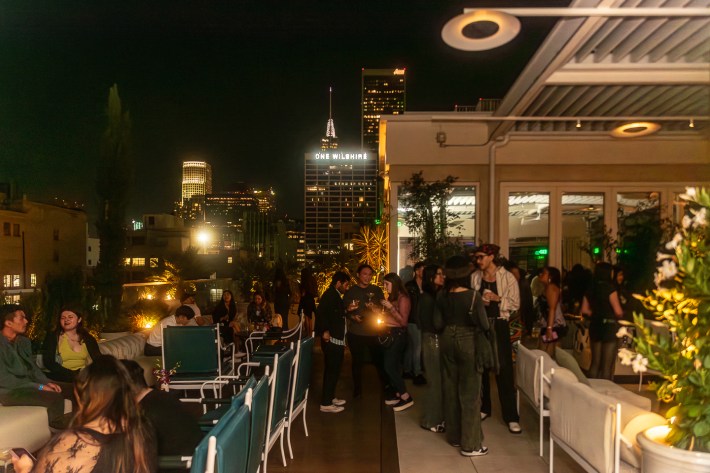 Attendees gather on a rooftop bar at night.