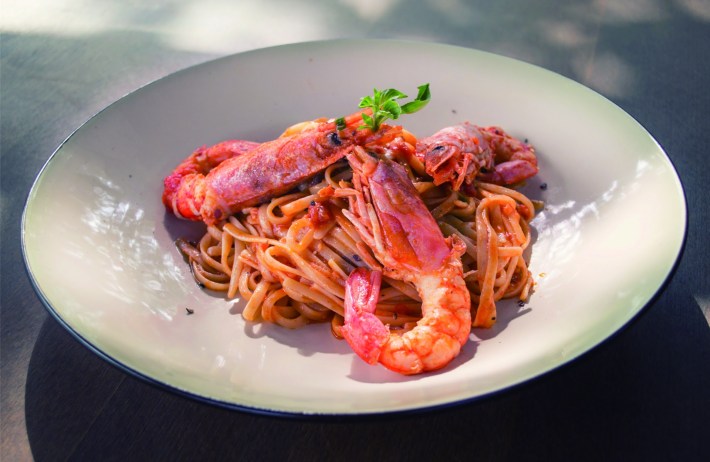 Crawfish on noodles in a white plate.
