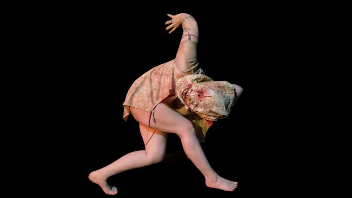 A figure with a distorted burlap sack over its head in a contorted standing position