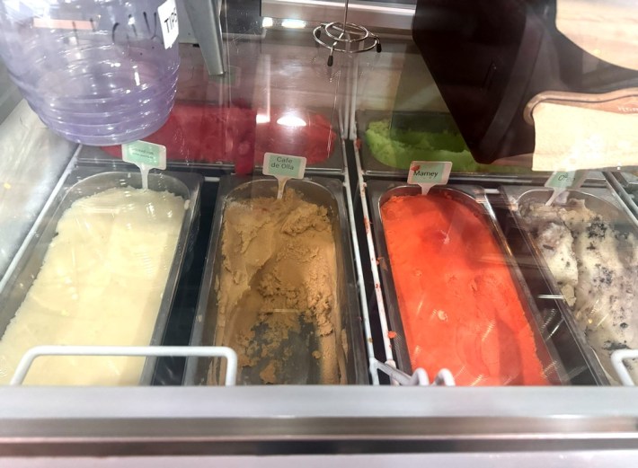 Four flavors of ice cream in steel tubs behind glass