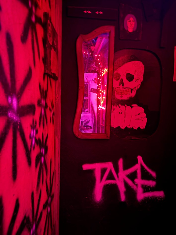The entryway to a haunted house has red lighting and a mirror