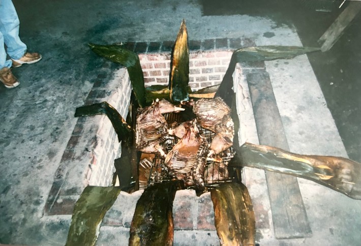 Meat is slow-cooked over a hole and leaves.