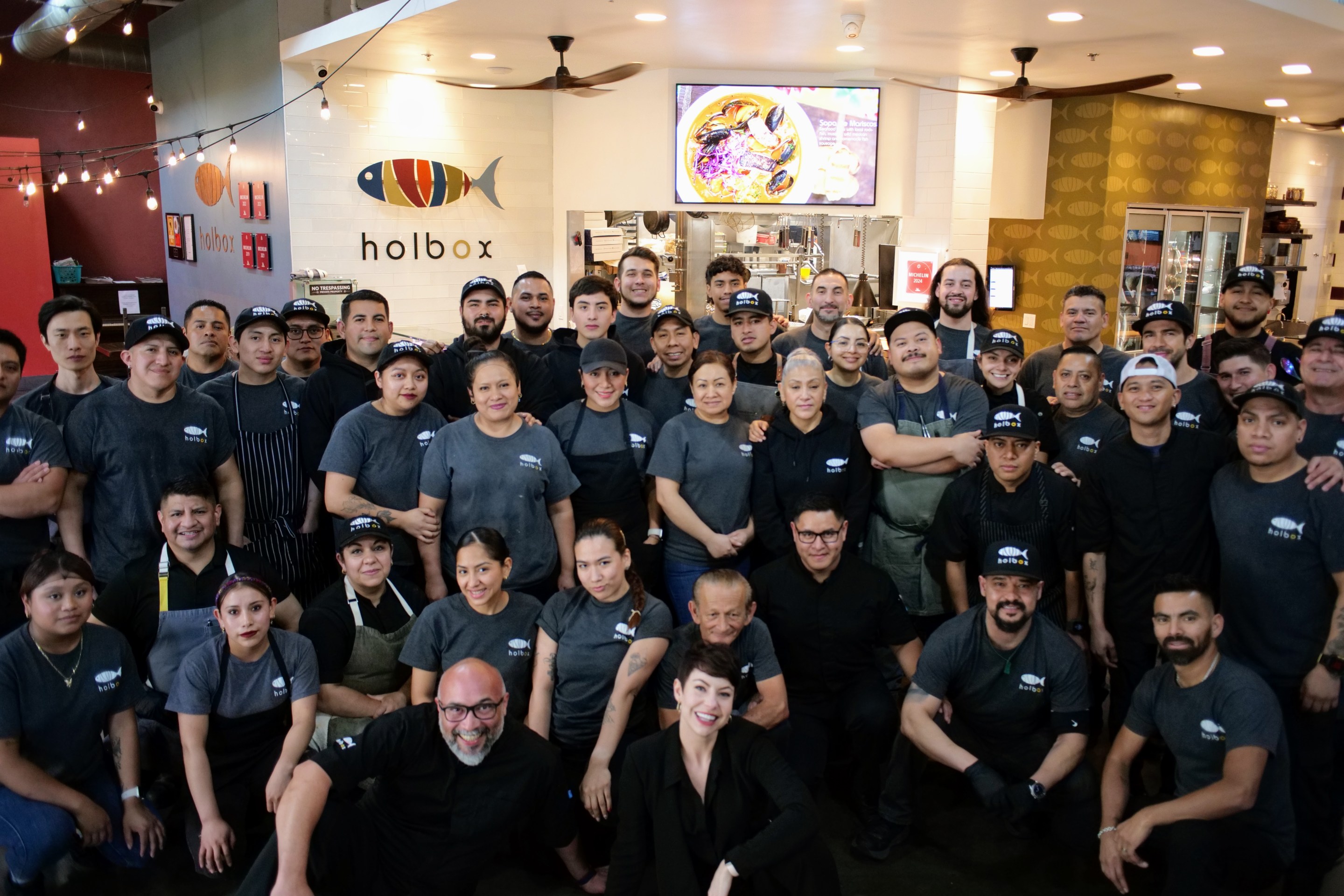 A team of cooks and servers pose in front of Holbox restaurant.