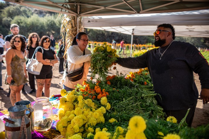 A man smiles while passing a bundle of flowers to a woman