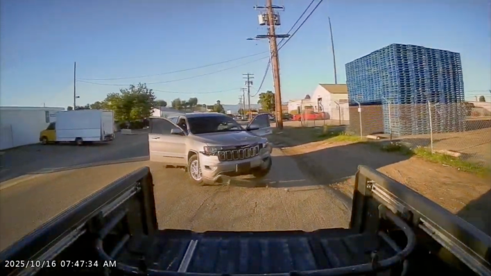 A silver Jeep is damaged after rear-ending a truck.