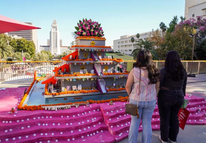 Two women stand in front of a large ofrenda.