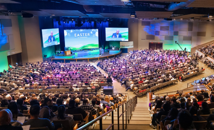 A large crowd of people observe an Easter service at a church.