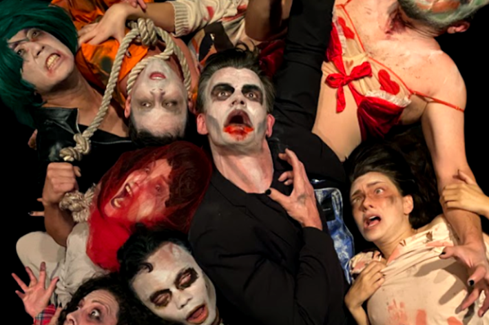 A group of horror actors with their stare open-mouthed at the camera in a gruesome circle