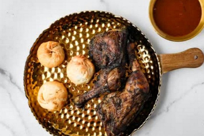 A copper pan with jerk chicken and dumplings